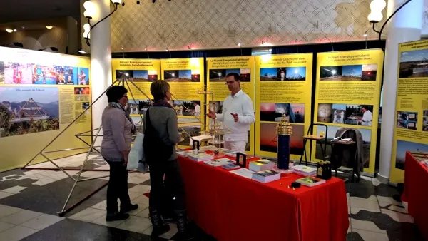 Mats Björkman im weißen Hemd erklärt zwei Besucherinnen am rot drapierten Messestand mit Horus Energiepyramiden-Modellen und gelben Infotafeln auf der Lebenskraft-Messe 2015 in Zürich.