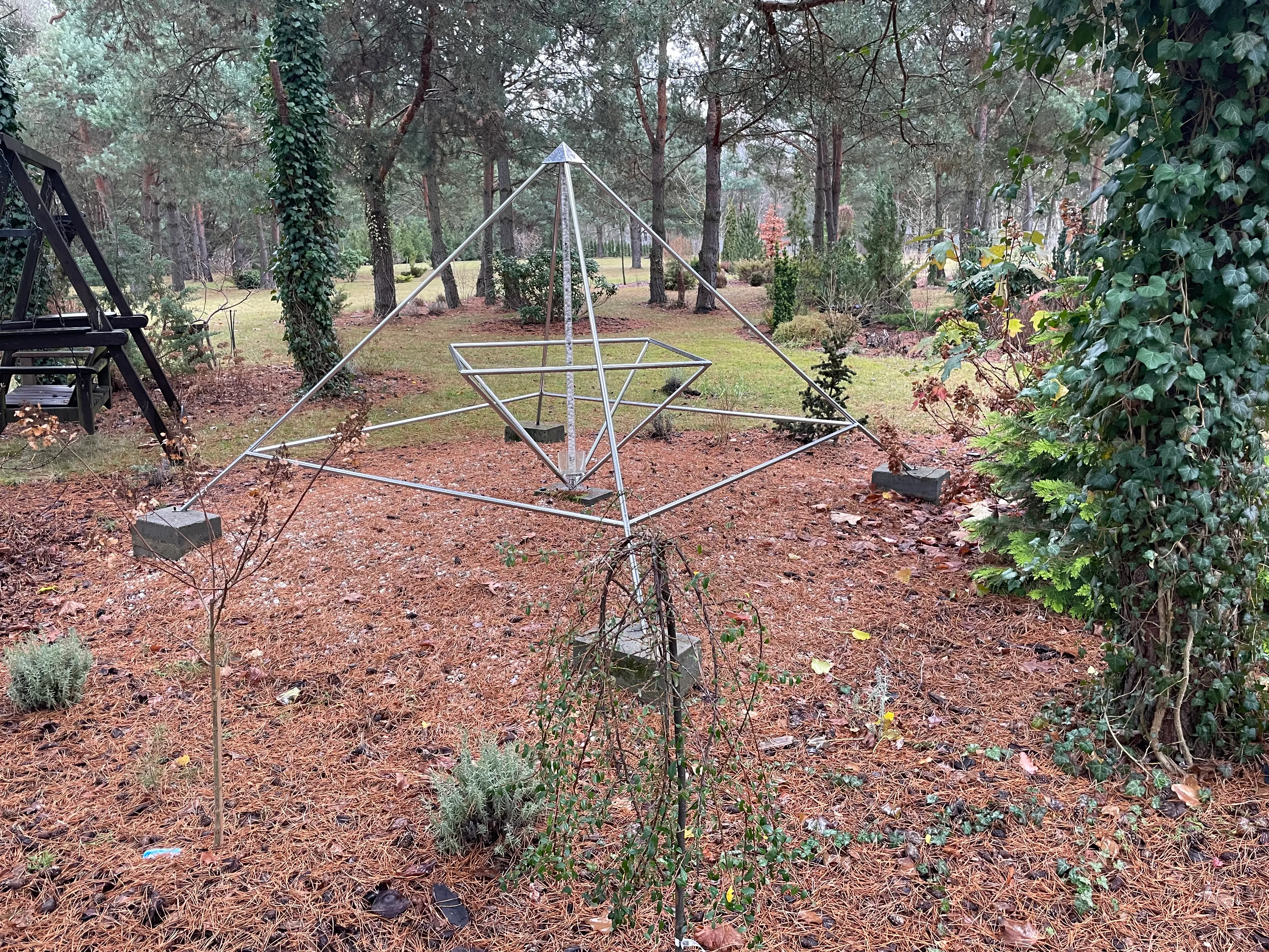 Dieselbe Energiepyramide Modell C in einem winterlichen Kiefern- und Heidegarten mit Lavendelbeeten.