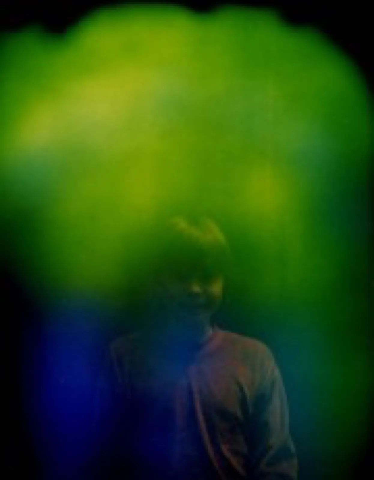 Aurafoto von 1997: Porträt einer Person in hellem Oberteil, über dem Kopf ein gelbgrüner Lichtschleier, der nach unten in Blau übergeht.