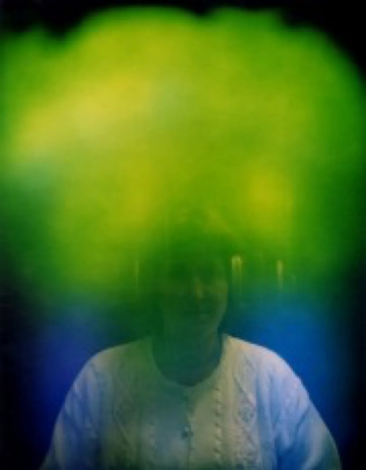 Aurafoto einer Person im weißen Zopfmusterpullover: Ein grüner Lichtschleier mit gelben Aufhellungen umgibt Kopf und Schultern, an den Seiten und unten geht er in Blau über.