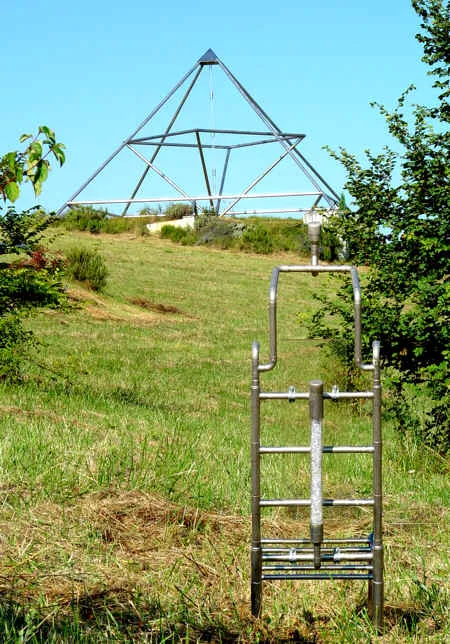 Metallener Pharaonenstuhl im Vordergrund, dahinter die 9-Meter-Energiepyramide auf dem Hügel