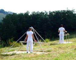 Zwei Menschen in Weiß meditieren bei einer Energiepyramide auf dem Feld von Le Braquet