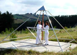 Zwei Frauen in Weiß stehen in einer Energiepyramide Modell D auf dem Feld von Le Braquet