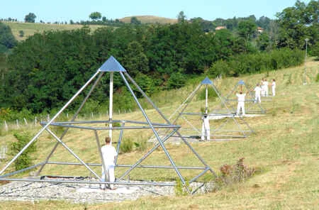 Eine Reihe Energiepyramiden in absteigender Größe auf einem Hang, Menschen in Weiß dazwischen (Le Braquet, 2007)
