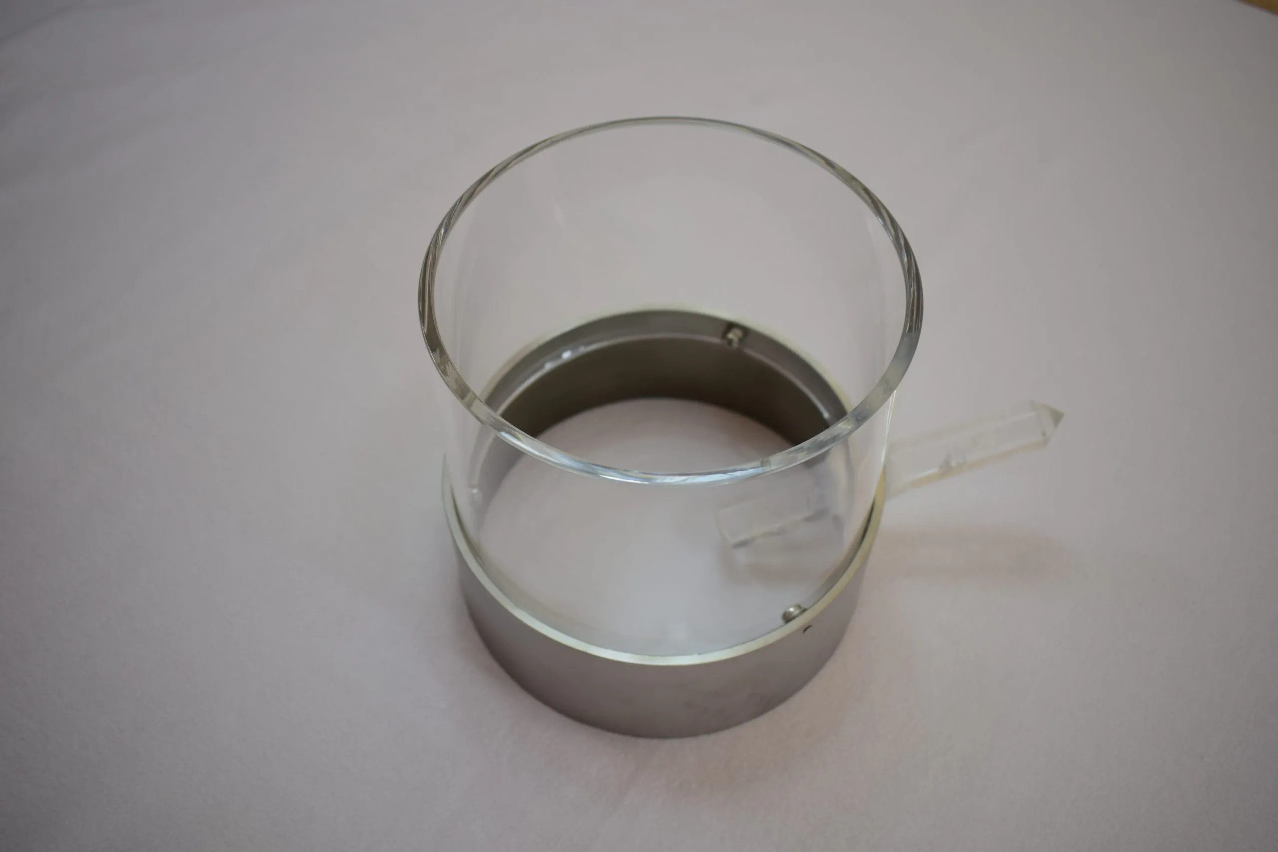 Horus-Ring: ein Stahlband um ein Acrylrohr mit einem kleinen Bergkristall an der Seite