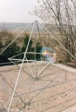 Energiepyramide Modell C auf einer Steinterrasse mit einem Regenbogen-Lichtreflex