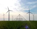 Energiepyramide Modell C auf einem Feld vor mehreren Windrädern in der Dämmerung