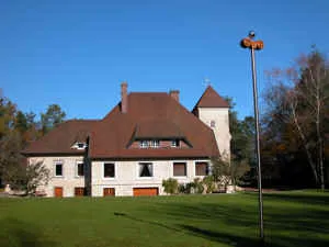 Großes Herrenhaus (Château Beaumont) mit Rasen und einer hohen Stele (Irminsul) im Vordergrund