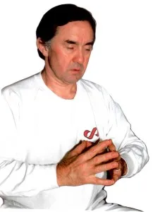 D. Harald Alke in weißem Shirt mit rotem Kyborg-Logo, die Hände meditativ vor der Brust – eine Energytraining-Haltung