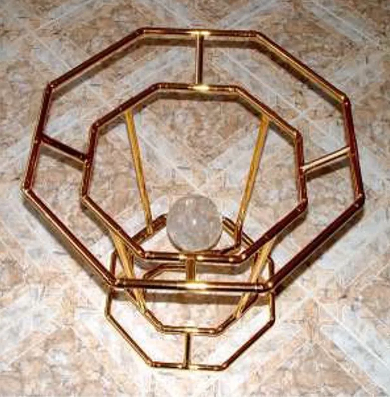 Der Horus-Brunnen schräg von oben auf gefliestem Boden: ineinander gesetzte goldene Achteck-Ringe (Bagua) mit einer Bergkristallkugel in der Mitte