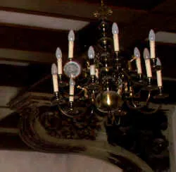 Messing-Kronleuchter mit Kerzenlampen an einer Holzdecke (Schloss in Schlesien)