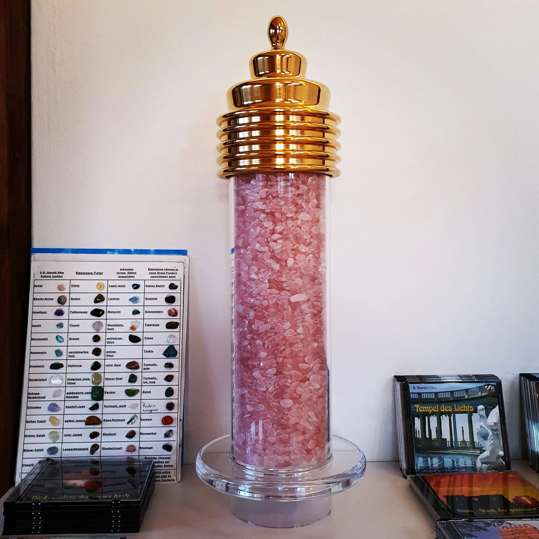 Mega Power Cap auf einer mit Rosenquarz gefüllten Acrylsäule, im Ausstellungsraum neben einer Edelstein-Tafel