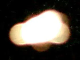 Nahaufnahme eines hellen, verschwommenen weißen Lichtflecks (Orb) auf schwarzem Grund