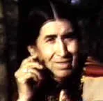 Farbporträt von Phillip Deer, einem indigenen Mann mit langem dunklem Haar und Stirnband, der lächelt