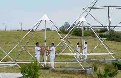 Mehrere Menschen in Weiß an zwei großen Energiepyramiden auf dem Hügel von Le Braquet