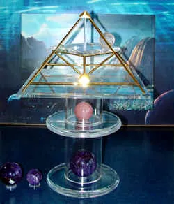 Energiepyramide Modell A auf einer Acryl-Säule mit Rosenquarz- und Amethystkugeln vor blauem Hintergrund
