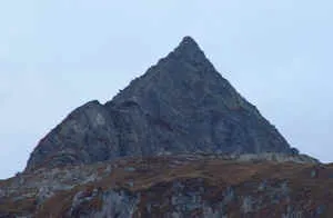 Steiler, pyramidenförmiger Felsgipfel in der Dämmerung (Graubünden, Schweiz)