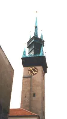 Der gotische Rathausturm von Znojmo (Znaim): ein hoher Steinturm mit reich verzierter, türkisgrüner Spitze mit mehreren Fialen, goldenen Knäufen und einer Turmuhr.
