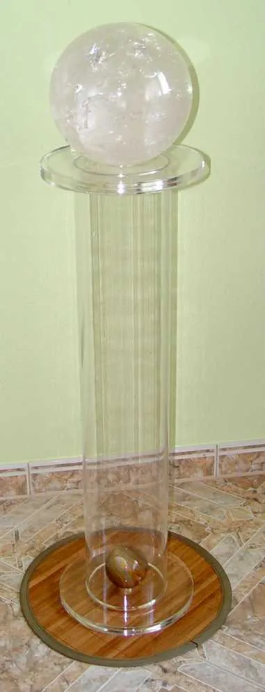 Klare Acrylsäule mit einer großen Bergkristallkugel oben, auf rundem Holzsockel